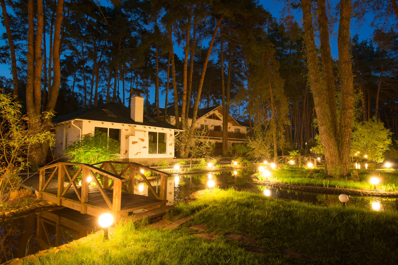 Outdoor landscape lights surrounding a home at dusk